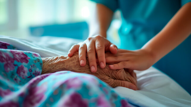 Close-up of nurse holding elderly hand, terminal care in hospital
