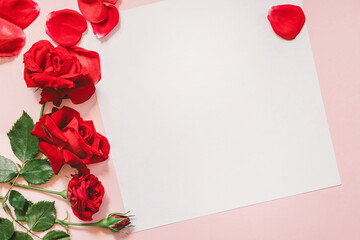 Valentine's day background with red roses and blank card on pink background