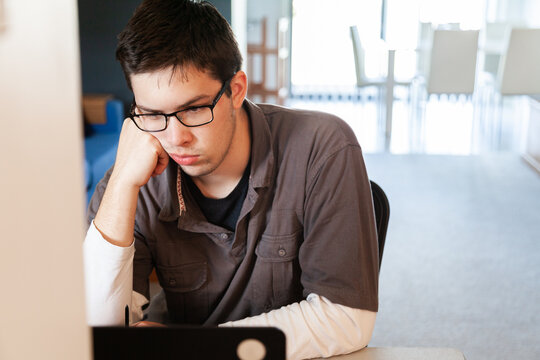 Young male uni student studying math on laptop for exams from home during covid-19