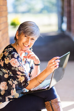 Portrait of a happy smiling middle aged woman working on her laptop outside