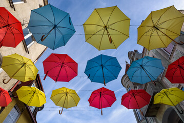 Fototapeta na wymiar CITY LANDSCAPE - Tenement houses and colorful umbrellas against the blue sky