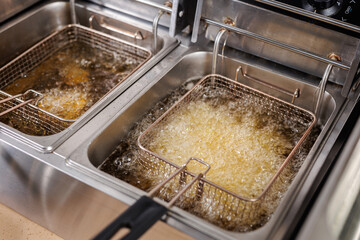 Frying potatoes in fryer for french fries in a restaurant.