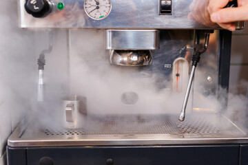 Coffee machine in steam, barista preparing coffee at cafe.