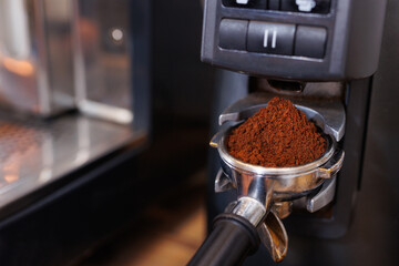 Macro shot of barista pressing ground coffee using tamper. Close-up view on hands.