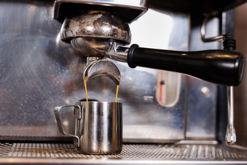 Close-up of espresso pouring from coffee machine. Professional coffee brewing.