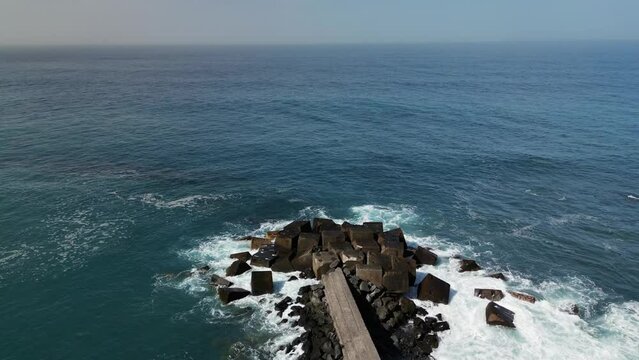 Aerial drone footage of ocean blue water waves and stone breakwater, Tenerife, Canary Island, Spain.