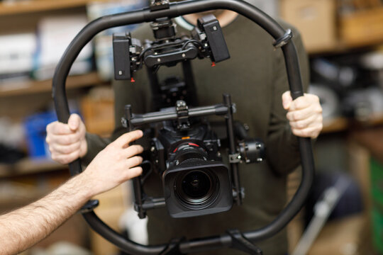 Professional videographer holding camera on gimbal rig steadycam to make video without shaking.