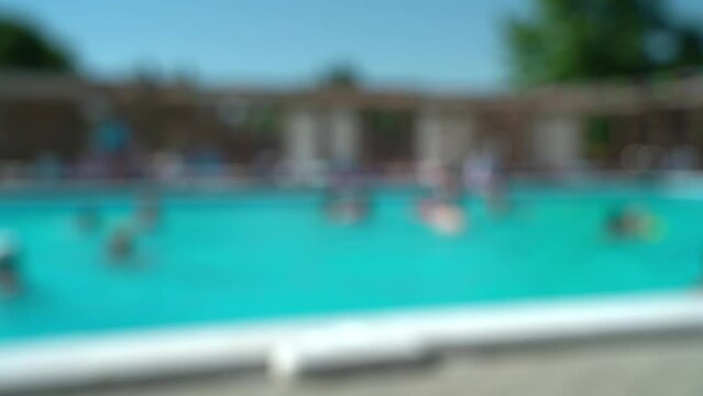 Abstract background of blurred hotel pool with blue water and swimming people. Defocused resort on summer day. Vacation, holiday, travel