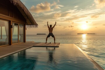 Man doing yoga on the terrace of a traditional luxury bungalow in Maldive islands at sunrise.  - obrazy, fototapety, plakaty
