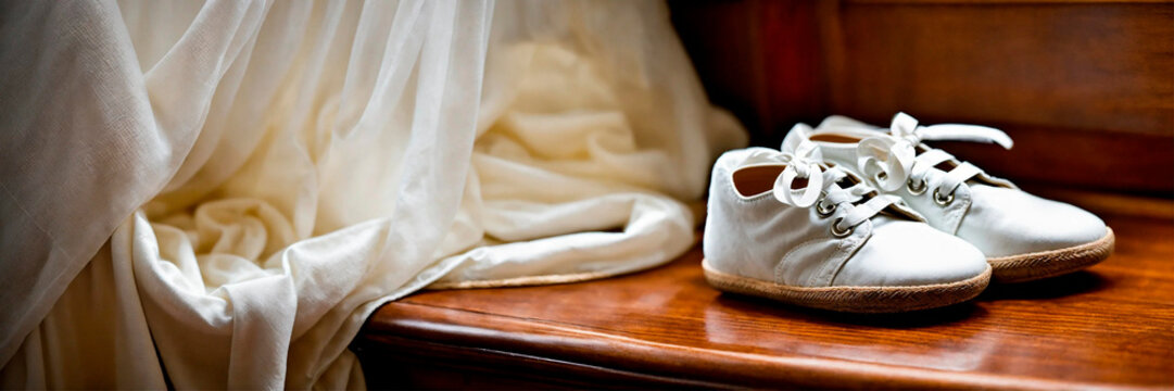 baby booties and a cross for baptism. Selective focus. - Powered by Adobe