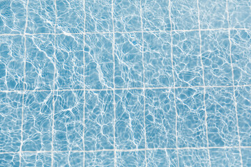 Clear water surface with ripple wave splashes and drops in swimming pool. Abstract turquoise or blue texture water wave and sunlight shadow reflections for background.