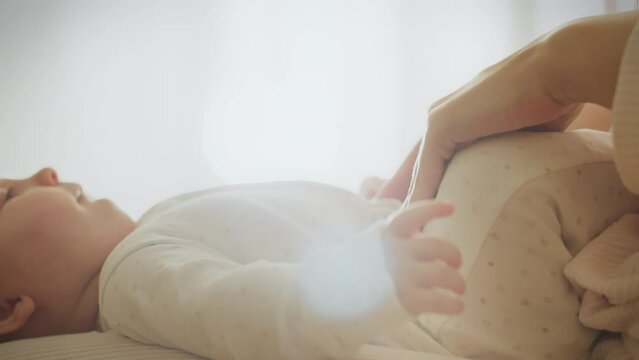 A caring mother pays special attention to the health of her newborn, giving abdominal massage to relieve his discomfort. Baby care techniques include the art of massage to relieve pain and colic