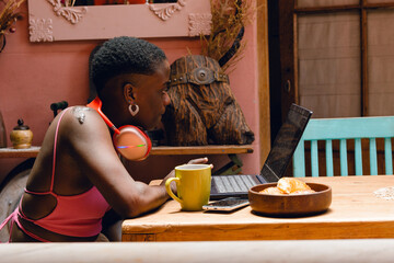 Fototapeta na wymiar young afro entrepreneur woman at home working with her laptop, analyzing her digital business