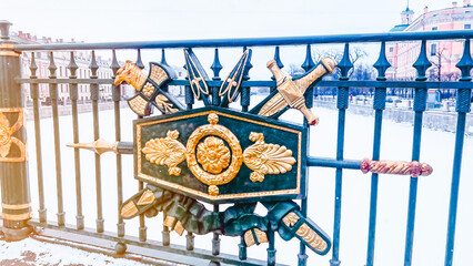 Close-up view of wrought military style ornament with arrows on metal rail. Golden sword and axe...