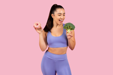 Cheerful woman choosing between donut and broccoli