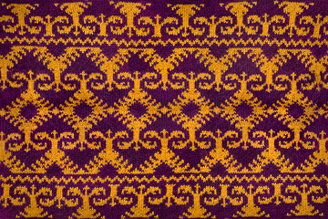 Close-up jacquard texture knitted on needles. Knitted background with orange and burgundy pattern
