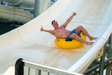 A man rides at high speed from a water slide in a water park.