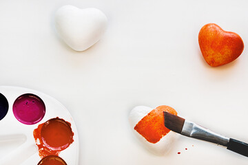White and red hearts are depicted on a white background, as well as a palette of colors. One heart is painted red with a brush. Kind and cold heart