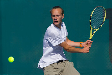 Tennis player playing tennis on a hard court on a bright sunny day