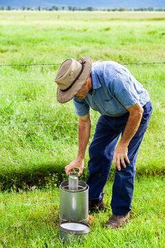 Farmer checking rain gauge after drought has broken and paddocks are green