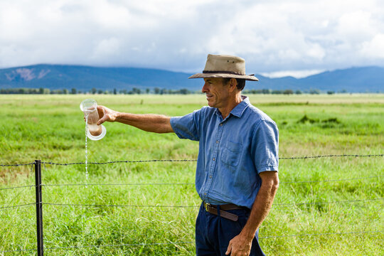 Farmer checking rain gauge after drought has broken and paddocks are green