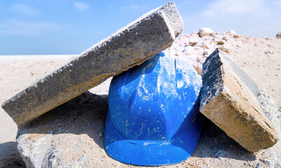 Hastily abandoned construction helmet in sand. Helmet is able to withstand impact of a concrete...