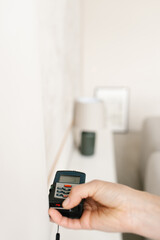 Laser rangefinder in the hands of a woman near a wall. Engineer holding laser rangefinder close up with copy space