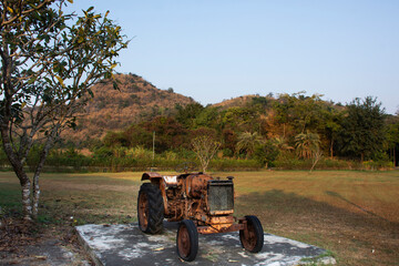 Old damage and broken engine vehicle tractor machine exhibit show in garden park with landscape mountain in Ban Rai for thai people travelers travel visit at Uthaithani city in Uthai Thani, Thailand - obrazy, fototapety, plakaty