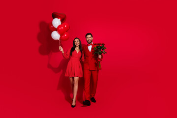 Full body photo of attractive young couple walk hold hands valentine day wear trendy elegant clothes isolated on red color background