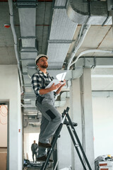 Checking the ceiling. Construction worker in uniform in empty unfinished room