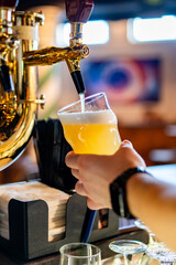 man bartender hand at beer tap pouring beer in glass in bar or pub
