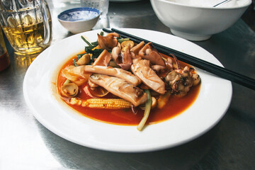 Plate with seafood. Vietnamese meal. Squid cuisine with chopsticks. Glass of beer next to a plate. Delicious Thai dish.