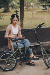 Obraz premium Happy young Asian woman while riding a bicycle in a city park. She smiled using the bicycle of transportation. Environmentally friendly concept.