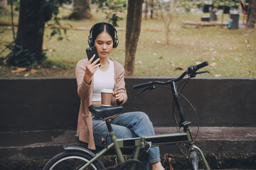 Obraz premium Happy young Asian woman while riding a bicycle in a city park. She smiled using the bicycle of transportation. Environmentally friendly concept.