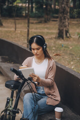 Obraz premium Happy young Asian woman while riding a bicycle in a city park. She smiled using the bicycle of transportation. Environmentally friendly concept.