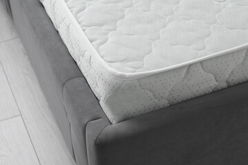 New soft mattress on grey bed indoors, closeup