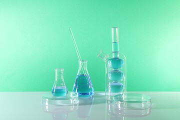 Laboratory analysis. Different glassware on table against green background