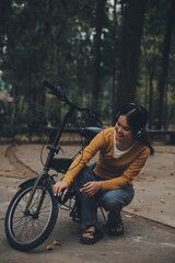 Obraz premium Happy young Asian woman while riding a bicycle in a city park. She smiled using the bicycle of transportation. Environmentally friendly concept.