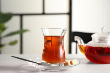 Traditional Turkish tea in glass and sugar cubes on white table