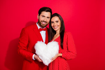 Portrait of lovely peaceful partners arms hold comfy fluffy heart figure pillow empty space isolated on red color background