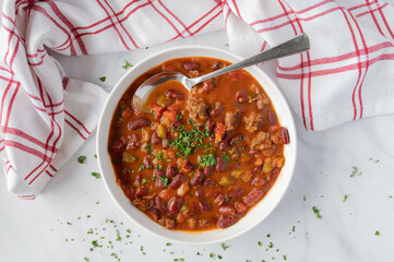 Low fat bean soup or bean stew mexican style with kidneybeans, lean ground beef, and vegetables on plate isolated on light background.