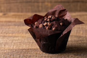 Chocolate dark muffin with chocolate chips and drops on a wooden table 
