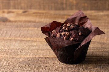 Chocolate dark muffin with chocolate chips and drops on a wooden table 
