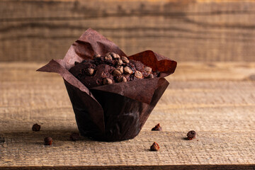 Chocolate dark muffin with chocolate chips and drops on a wooden table 