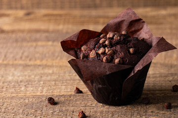 Chocolate dark muffin with chocolate chips and drops on a wooden table 