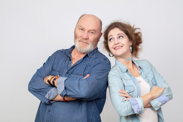 An adult daughter with an elderly father in denim clothes posing and looking at the camera. Daughter-in-law and father-in-law on a gray background.