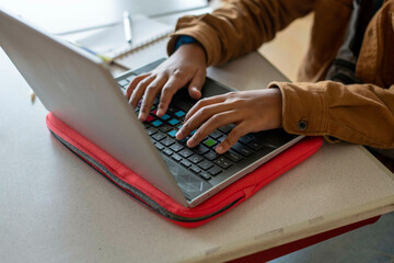 Close up of a mixed raced student working on his laptop in class 