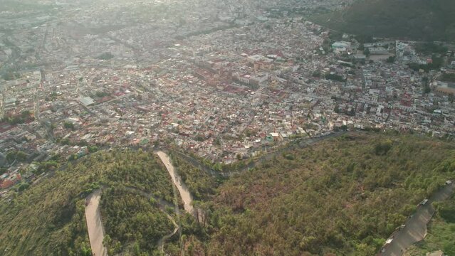 Aerial drone footage captures the stunning cityscape of Zacatecas from Cerro de la Bufa, descending to reveal the historic center's narrow streets and alleys. Explore the beauty of Mexico from above