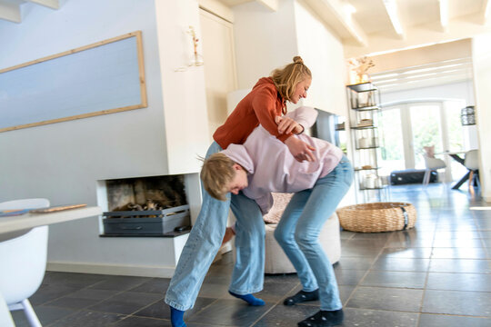 Brother and sister play fighting in their modern living room bright and aery 