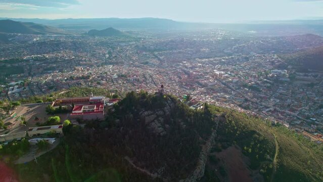 Drone footage orbits around Cerro de la Bufa in Zacatecas, focusing on its iconic lighthouse with a smooth lateral movement, showcasing the stunning cityscape
